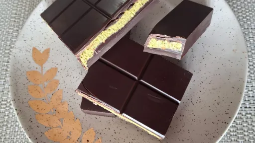 Dark chocolate pieces with creamy pistachio filling on a speckled plate.