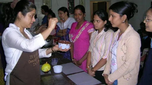 Nita in apron demonstrates chocolate making to an attentive group of women.