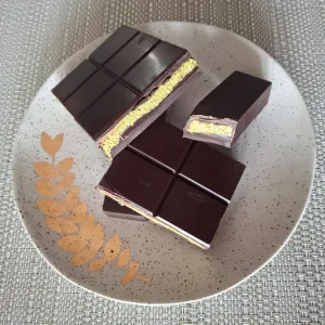 Dark chocolate pieces with creamy pistachio filling on a speckled plate.