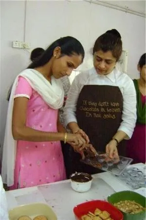 Teaching a visually impaired girl on filling a mould with chocolate